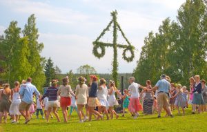Akersberga, Stockholm, Sweden - June 21, 2013: Summer dressed beautiful people dance in a traditional ring around the birch leaf clad Midsummer pole at Summer Solstice on June 21, 2013 in Akersberga, Stockholm, Sweden