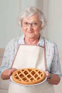 Happy smiling senior woman showing her apricot tart.